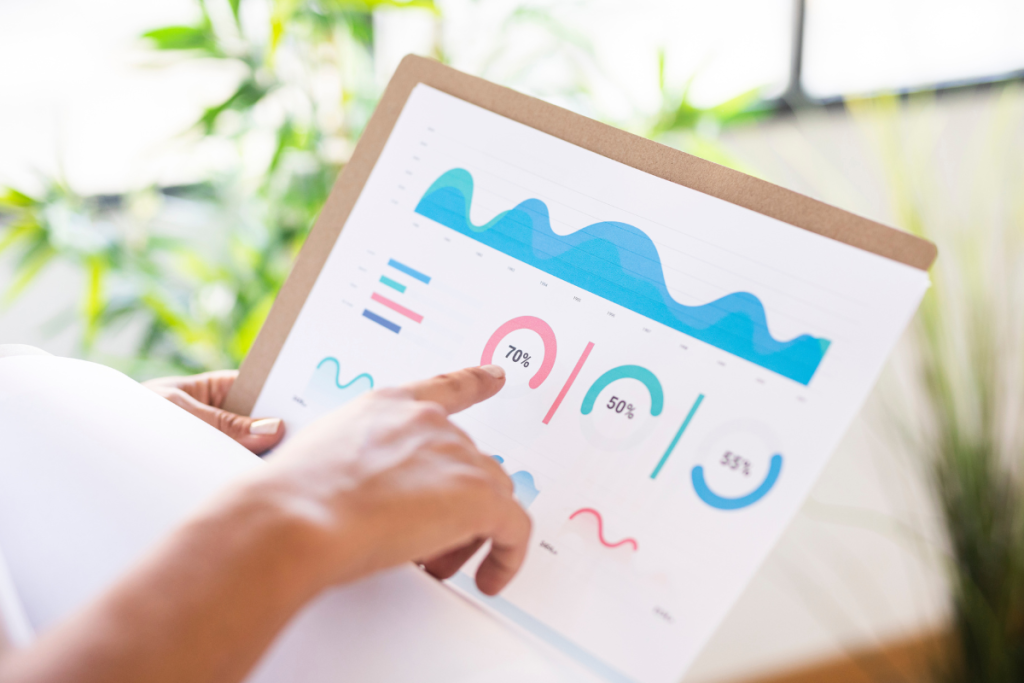 A imagem mostra uma pessoa segurando uma prancheta com um relatório impresso que exibe gráficos e indicadores de desempenho coloridos.