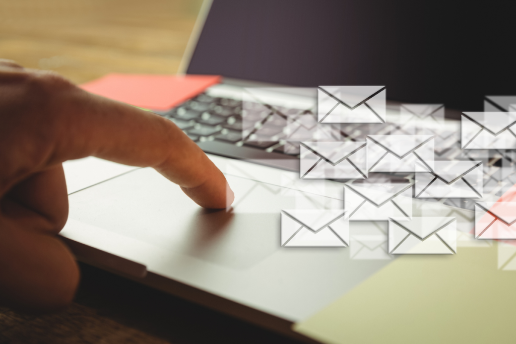 A imagem mostra um close-up da mão de uma pessoa prestes a tocar no touchpad de um notebook, sugerindo a ação de enviar ou gerenciar algo digitalmente como um remarketing